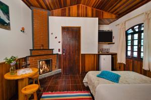 a bedroom with a fireplace and a bed and a table at Pousada do Rio Maua in Visconde De Maua