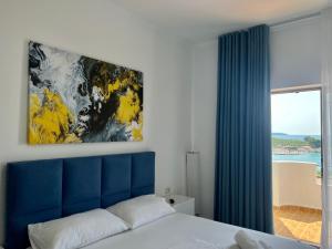 a bedroom with a blue headboard and a painting above a bed at Dine Apartments in Ksamil