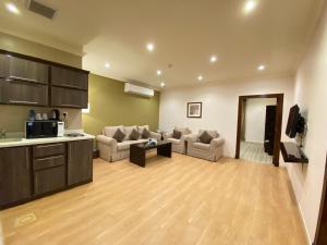 a living room with two couches and a kitchen at فندق ضيافة القرية Al Diyafa Hotel in Al Ahsa