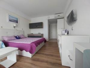 a bedroom with a bed with a purple blanket at Blaxy Resort STEFI in Douăzeci şi Trei August