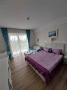 a bedroom with a large bed with a purple blanket at Blaxy Resort STEFI in Douăzeci şi Trei August