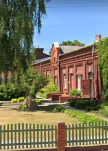 una valla frente a un edificio de ladrillo rojo en Nākotnes street apartaments en Liepāja