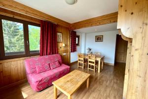 un soggiorno con un divano rosso e un tavolo di Bright 50 m cocoon with balcony in Combloux a Combloux