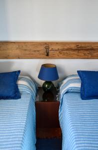 a bedroom with two beds with blue pillows and a lamp at Country Loft at Palazzo di Bagnaia in Castel del Piano