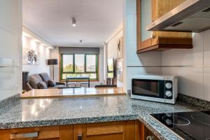 a kitchen with a microwave and a living room at Apartamento La orilla in Arrecife