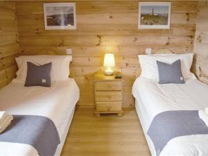 two twin beds in a room with wooden walls at Inver Lodge, Finsbay in Manish