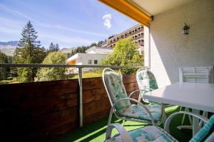 een patio met een tafel en stoelen op een balkon bij Rothornblick 19 in Arosa