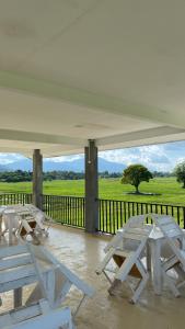 a group of picnic tables on a porch with a view of a field at LamanLeman Langkawi in Pantai Cenang