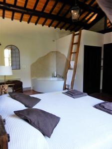 um quarto com uma grande cama branca e uma banheira em Country Loft at Palazzo di Bagnaia em Castel del Piano