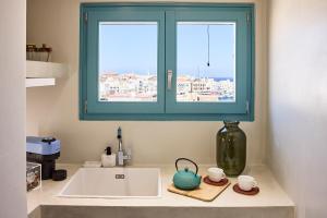 a kitchen counter with a sink and a window at Syroc Maison in Ermoupoli