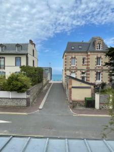 une rue vide avec deux bâtiments et l'océan dans l'établissement Villa Blanche, à Agon-Coutainville