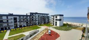 an apartment building with a tennis court and the beach at Gardenia Seaside Apartament 34 in Dziwnów