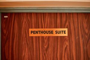 eine Holztür mit einem Schild, auf dem die Penthouse-Suite angezeigt wird in der Unterkunft seven skies hotel in Arusha
