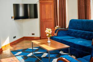 seven skies hotel في أروشا: غرفة معيشة مع أريكة زرقاء وطاولة