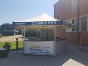 a lounge bar with a sign on top of it at Eliopoli Beach Hostel & Restaurant in Tirrenia