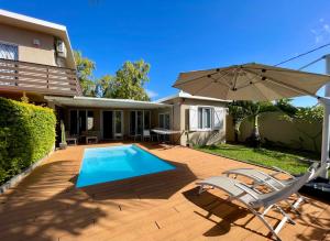 a patio with a swimming pool and an umbrella at Villas Hibiscus in La Gaulette