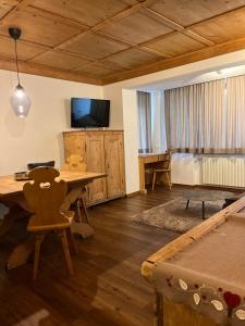 a living room with a wooden table and a television at Ciasa Agreiter in La Villa