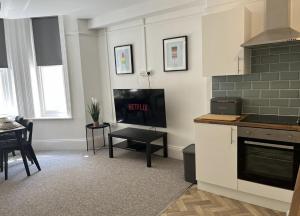 uma cozinha com uma televisão e uma mesa num quarto em Urban Living - Flat 2 em Bournemouth