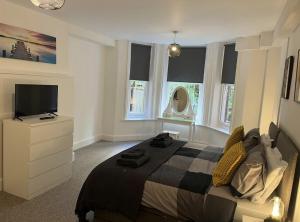 a bedroom with a bed and a tv and windows at Urban Living - Flat 2 in Bournemouth