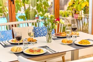 una mesa con platos de comida y copas de vino en Leonardo Suites Hotel Ibiza Santa Eulalia en Es Cana