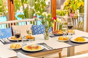 a table with plates of food and glasses of wine at Leonardo Suites Hotel Ibiza Santa Eulalia in Es Cana