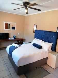 a bedroom with a large bed with a blue headboard at Butterflytree Guest House in Phalaborwa