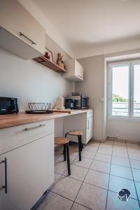eine Küche mit weißen Schränken und einem Fenster in der Unterkunft Superbe Appartement centre ville in Pont-Saint-Esprit