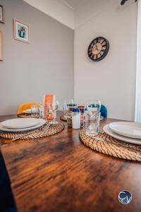 einem Holztisch mit Tellern und Gläsern darauf in der Unterkunft Superbe Appartement centre ville in Pont-Saint-Esprit