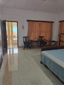a bedroom with a bed and chairs and a table at Akkara Homestay & Ayurveda in Kottayam