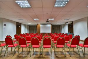 a conference room with red chairs and a screen at MG Flats Hotel & Residence in Cuiabá