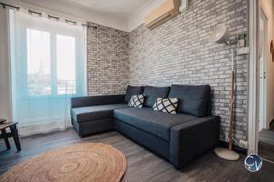 ein Wohnzimmer mit einem blauen Sofa und einer Ziegelwand in der Unterkunft Superbe Appartement centre ville in Pont-Saint-Esprit