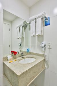 a bathroom with a sink and a mirror and towels at MG Flats Hotel & Residence in Cuiabá