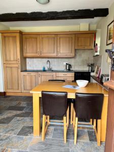eine Küche mit Holzschränken und einem Holztisch mit Stühlen in der Unterkunft The Barn at Walker Ground Manor in Hawkshead