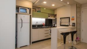ベント・ゴンサルベスにあるApartamento Luxo em Bento Gonçalvesのキッチン(冷蔵庫付)、カウンター(スツール付)
