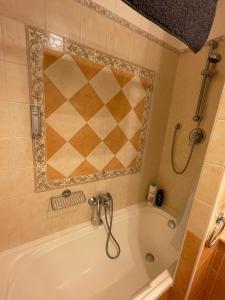 a bathroom with a tub with a mosaic tile wall at Tristan casa vacanze a Roma in Casal Palocco