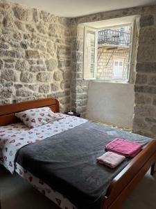 uma cama num quarto com uma parede de tijolos em Apartman Dado em Perast