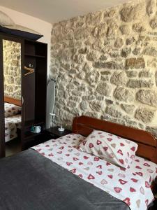 uma cama num quarto com uma parede de pedra em Apartman Dado em Perast