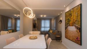 uma sala de jantar com uma mesa branca e uma sala de estar em Apto Luxo Vila di Tondo Area Lazer na Cobertura em Bento Gonçalves