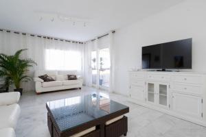 sala de estar blanca con TV y sofá en Reserva de Marbella, en Marbella