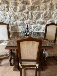 a table with a bottle of wine and two chairs at Apartman Dado in Perast