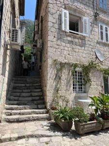 un viejo edificio de piedra con escaleras y un hombre caminando por él en Apartman Dado, en Perast