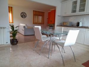 uma cozinha e sala de estar com uma mesa de vidro e cadeiras brancas em Casa da Avo dos Anjos em Casais de São Mamede