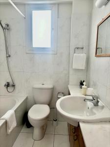 a white bathroom with a toilet and a sink at Sayers Beachfront Villa in Pervolia