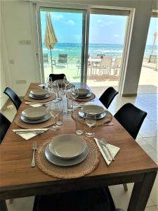 een houten tafel met borden en wijnglazen erop bij Sayers Beachfront Villa in Perivolia