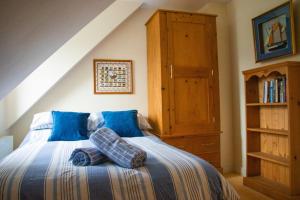 a bedroom with a bed with blue sheets and a wooden cabinet at Beach Side Top Floor Property, Balcony & Sea Views in Newquay