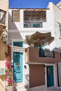 un edificio con puertas azules y sombrilla en Syroc Maison en Ermoupoli