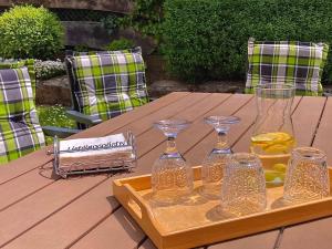 a wooden table with a tray with wine glasses on it at Ferienwohnung Gerne-Da in Großrinderfeld