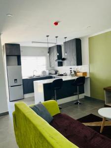 a living room with a yellow couch and a kitchen at Comfy Zone Apartment in Gaborone
