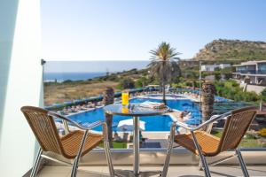 a table and chairs on a balcony with a view of a pool at Cathrin Hotel in Faliraki