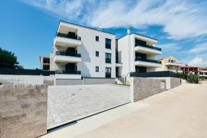 a white building with a fence in front of it at Apartments San Maris in Umag
